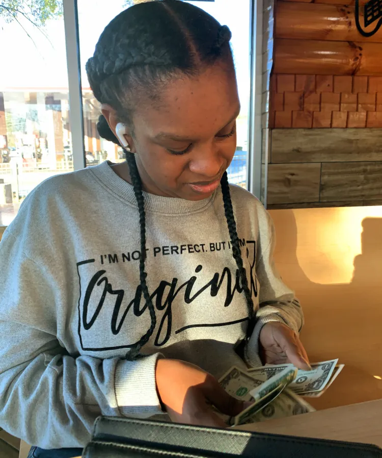 Young woman counting dollar bills while practicing financial literacy skills