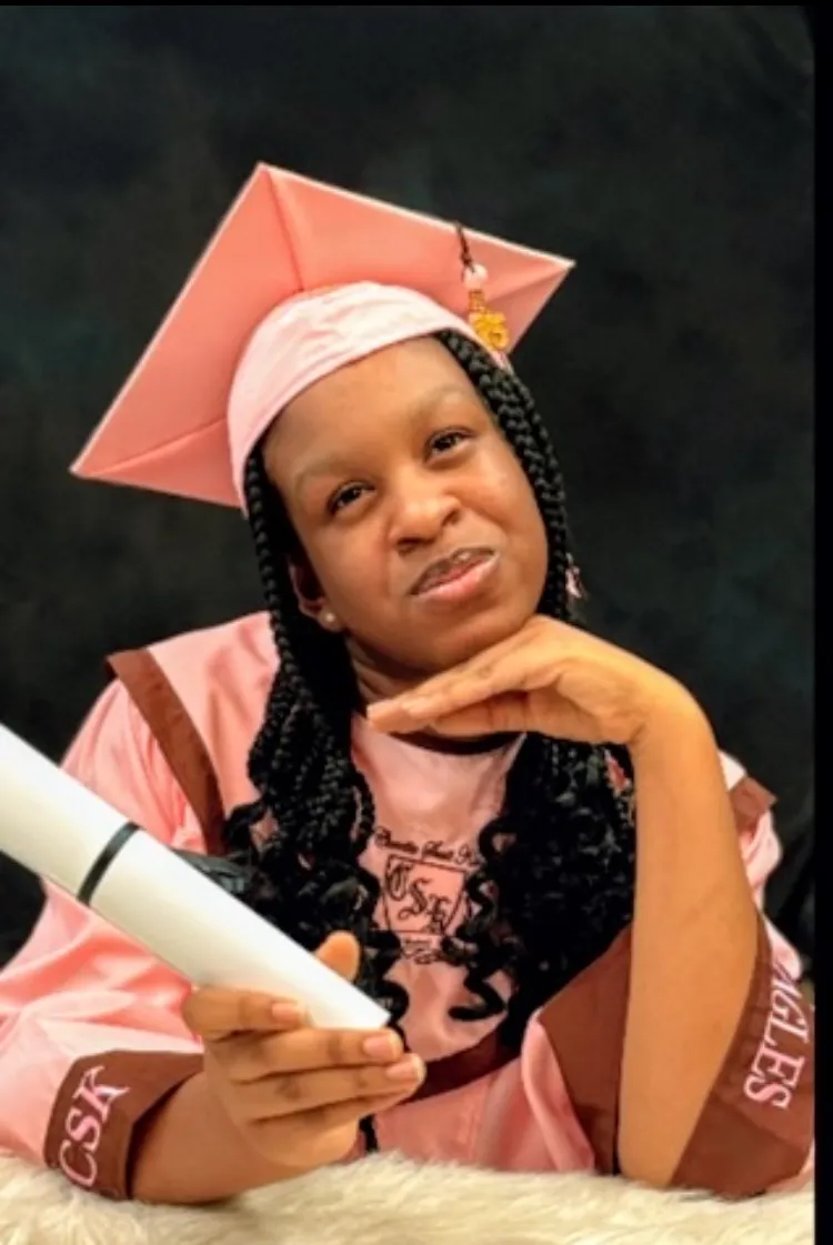 Joi in her pink cap and gown holding her high school diploma