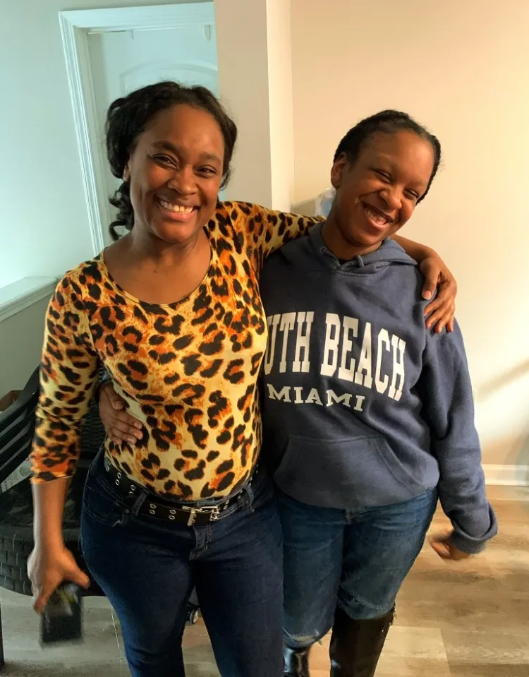 Two women smiling and hugging at a JCATF community gathering